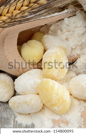 Wooden table with a sack of flour and spoon with ears and dumplings