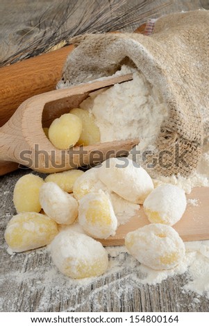Wooden table with a sack of flour and spoon with ears and dumplings