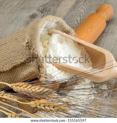 Wooden table with a sack of flour and spoon with ears