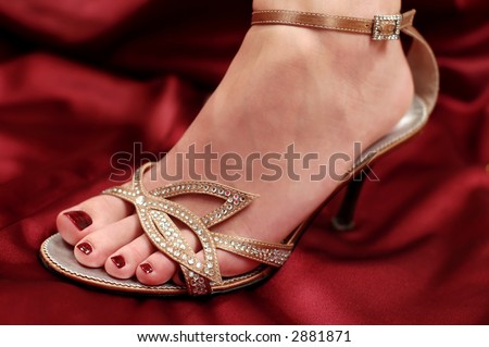 Woman leg in small shoe with heel on red satin.