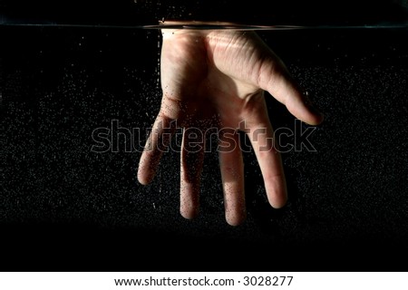 Photo of hand in the water on a black background.