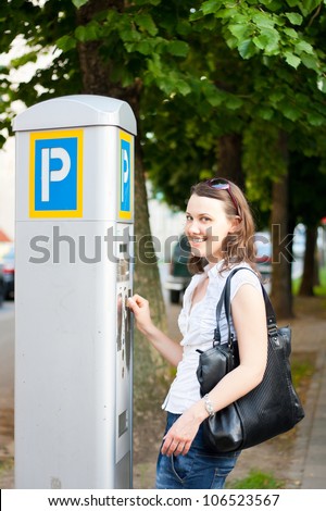 Young woman paying for parking in the street