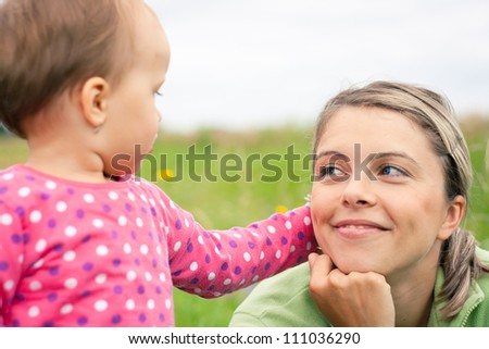 Young mother and her baby girl playing while outdoors on a walk