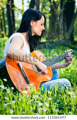 Young woman playing the guitar outdoors