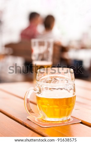 Close-up of a half-filled beer mug on a table in a city restaurant outdoor area