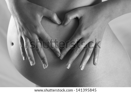 Woman in pregnant makes a heart shape with her fingers Woman in pregnant makes a heart shape with her fingers