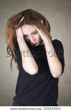 Depression concept - Woman catching her head with her hands on brown grey background