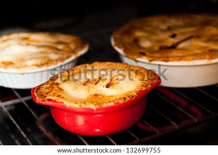 three apple pies cooking in the oven