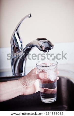 Thirsty man filling a glass of water