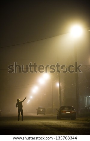 Woman alone in the middle of the foggy street pointing at something