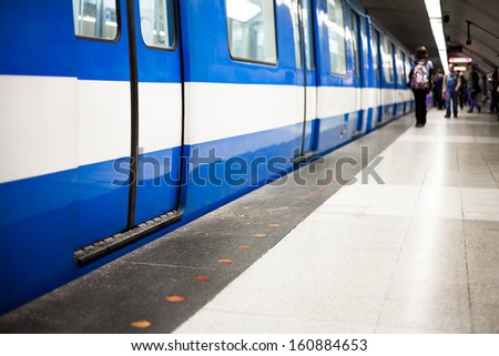 Colorful Underground Subway Train With Blurry People On The Platform. Focus Is On The Door. Room For Your Text.