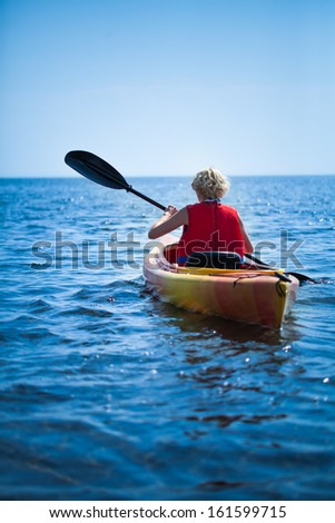 Young Woman Wearing a Safety Vest Heading out to sea Alone on Calm Water