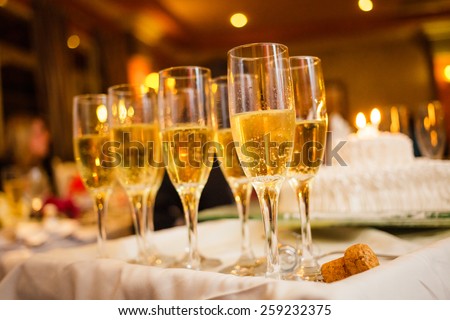 Many Champagne Glasses on a Tray with Anniversary Cake in Background