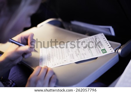 Woman Filling Document in the Airplane - blur motion of hand and personal informations erased.