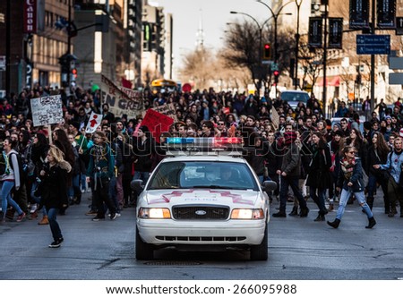 MONTREAL, CANADA   APRIL 02 2015: Riot in the Montreal Streets to counter the Economic Austerity Measures. Police Car in front of the Protesters controlling the Traffic