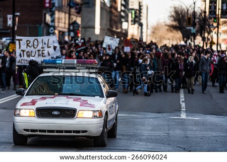 MONTREAL, CANADA   APRIL 02 2015: Riot in the Montreal Streets to counter the Economic Austerity Measures. Police Car in front of the Protesters controlling the Traffic
