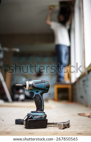 Battery Drill on the Floor with Worker in Background