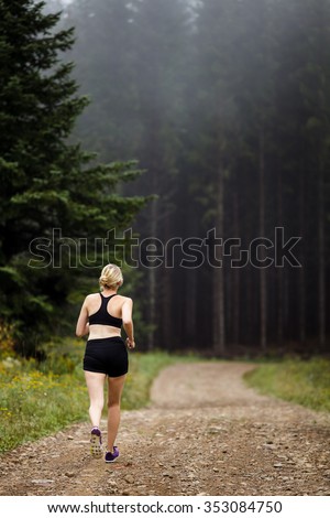 Female Jogger Training in Forest early in the Morning on a Foggy day of Autumn or Spring