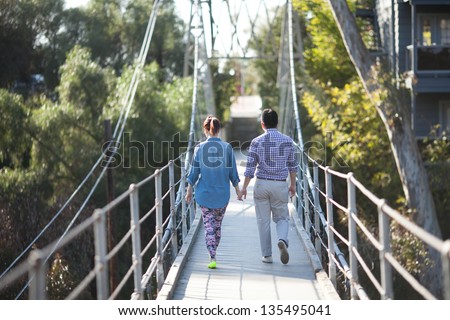 Couple walking away on suspension bridge