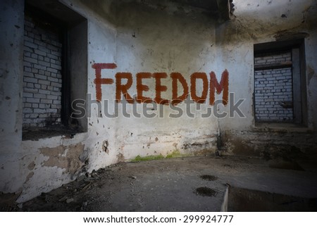 text freedom on the dirty old wall in an abandoned ruined house