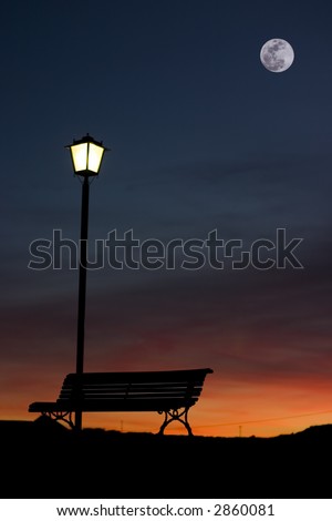 Back-lighting of a streetlamp bench and a at the dusk