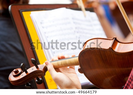 man playing the violin with a musical score in the background