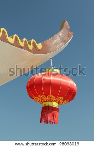 Red Chinese Lantern hanging on edge of concrete roof against blue sky