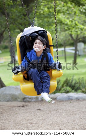 Happy disabled boy on yellow handicap swing