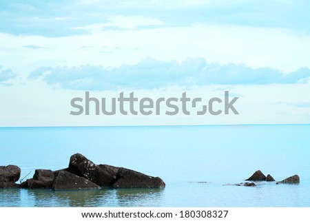 Water\'s edge on a calm day. Rocks in foreground