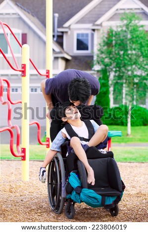 Disabled boy in wheelchair with big brother at park