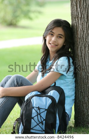 stock photo Young teen girl sitting against tree with backpack Part Asian 