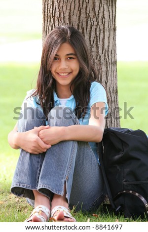 stock photo Young teen girl sitting against tree with backpack Part Asian 