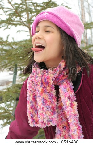 Nine year old girl sticking out her tongue trying to catch a snowflake
