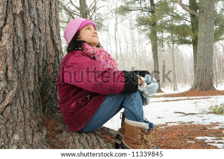 Nine year old girl enjoying sitting under tree in winter