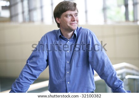 Handsome businessman smiling , relaxed in  large office complex
