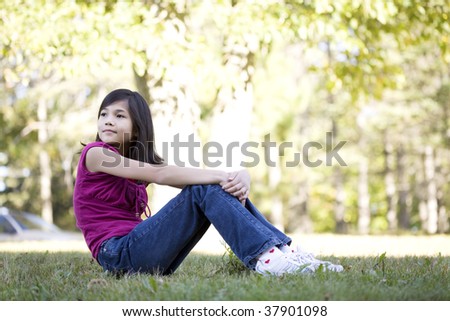 Little girl sitting on grass looking over shoulder