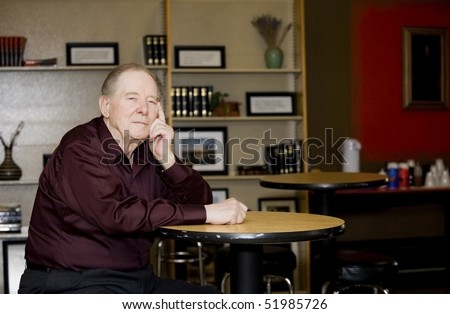 Elderly man in coffee shop, sitting alone at a table