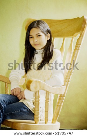 Girl in rocking chair looking out window, thoughtful look