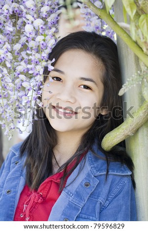 Beautiful young pre- teen girl standing under wisteria vines