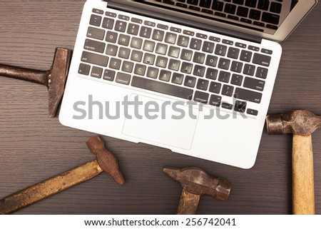 Modern laptop and old-fashioned hammers. Cross-processed image.