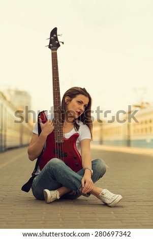 Girl with a guitar at train station. Retro toned image
