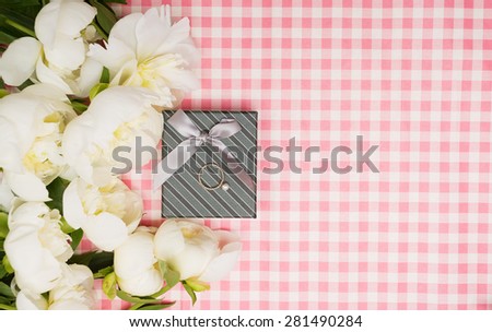Gift box with a bouquet of peonies on a pink background