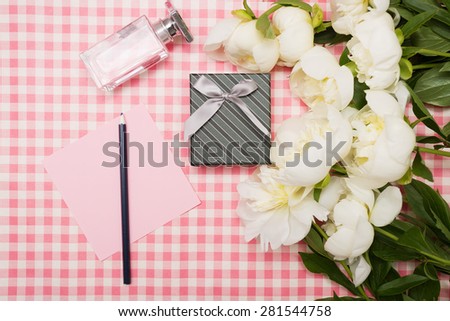 Gift box and a bouquet of peonies on a pink background