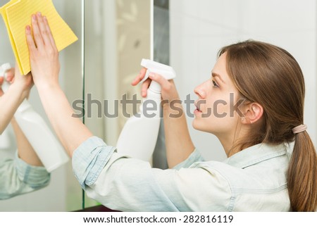Beautiful young girl cleaning up her house