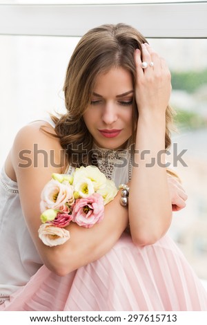 Romantic girl with flowers sitting by the window