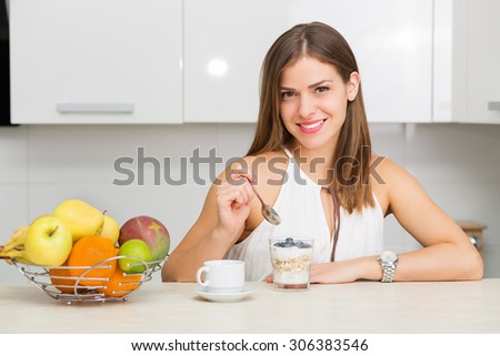 Beautiful woman having coffee, fruits and oatmeal for breakfast