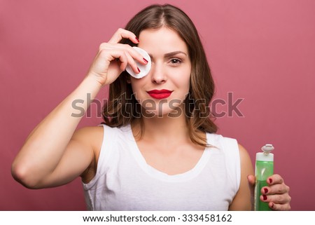 Woman cleaning her face with a lotion and a cotton pad