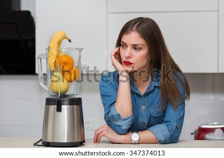 Beautiful woman using blender at her kitchen