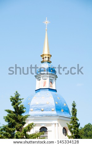 Blue dome with gold stars and a cross against a blue sky.