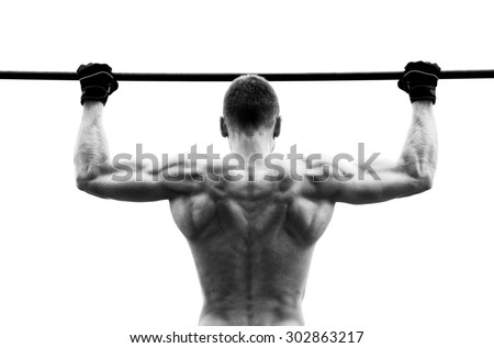 Muscle man making pull-up on horizontal bar against the sky